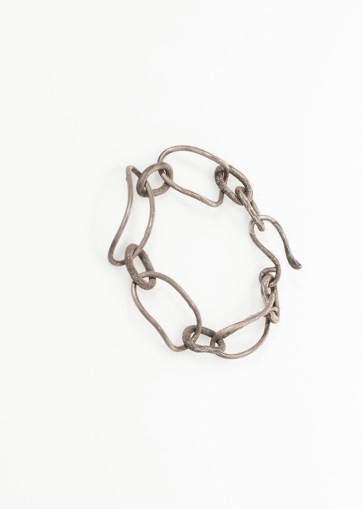 Chunky silver chain link bracelet with irregular oval links on white background