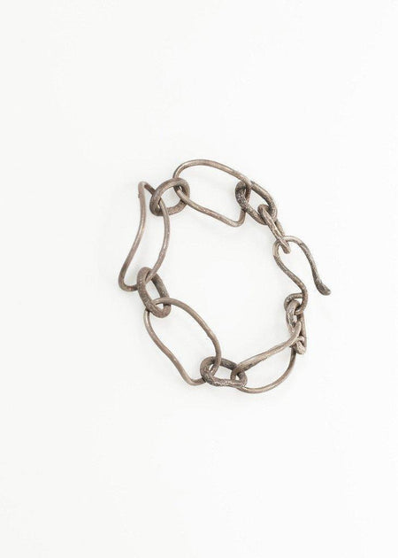 Chunky silver chain link bracelet with irregular oval links on white background